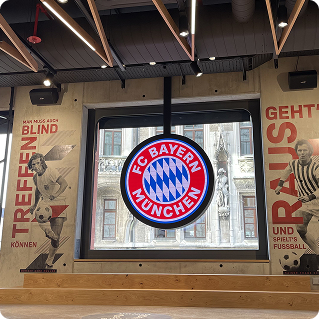 Wanddruck im FC Bayern München Fanshop – Logo und Graffiti-Schriftzüge auf Betonwand