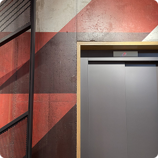 Detailaufnahme Wanddruck FC Bayern München – rot-graue Markenstreifen auf Beton neben Aufzug