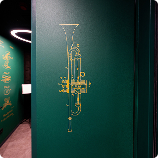 Detailaufnahme Wanddruck Thomann – goldener technischer Trompetenzeichnung direkt auf grüner Wand