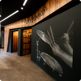Thomann Playground Showroom – Wanddruck mit Schlagzeug-Motiv auf dunkler Wand im Holzinterieur
